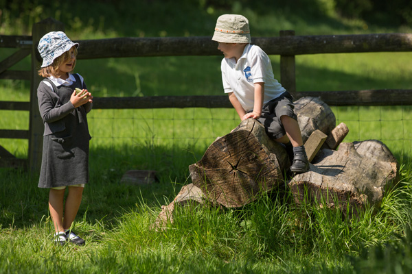 Girl laughing with boy on a log (Grantham Farm Montessori School)